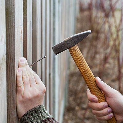 Hammer hitting a nail into a fence