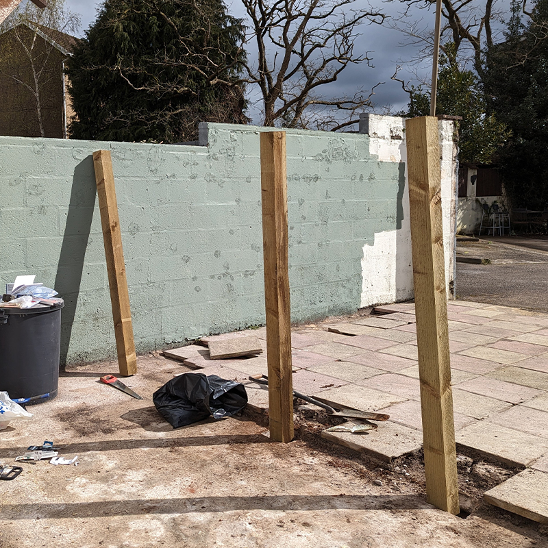 in-progress wooden fence post installation